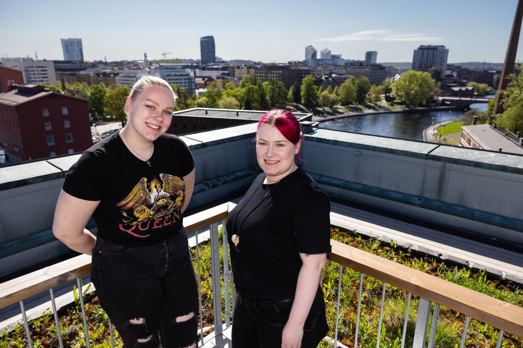 Vaaleahiuksinen Tilda Tamminen ja punahiuksinen Satu Turunen seisovat kattoterassilla puutarhan edessä.
